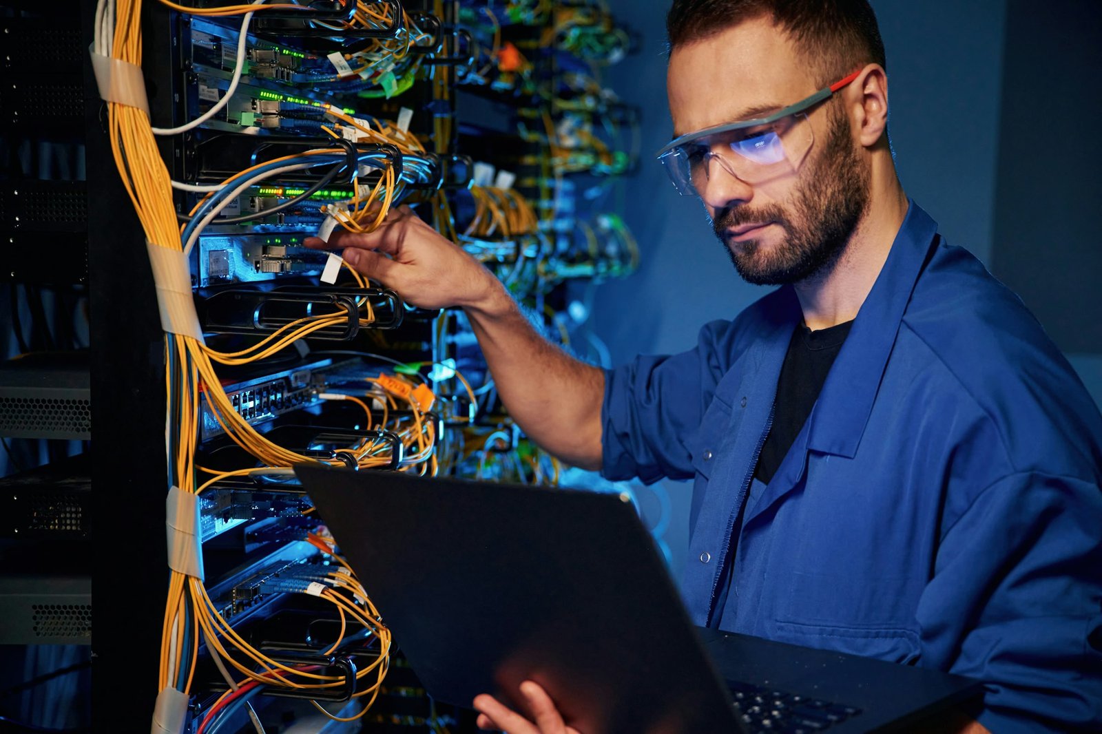 Cables management. Young man is working with internet equipment and wires in server room